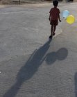 Menino de pé na rua segurando balões — Fotografia de Stock