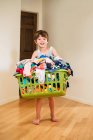 Sorrindo menino carregando cesta de roupa cheia de roupas — Fotografia de Stock