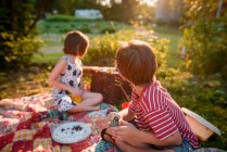 Dos niños pequeños haciendo un picnic por la noche - foto de stock