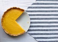 Нарезанный лимонный пирог на белой тарелке над раздетым полотенцем — стоковое фото
