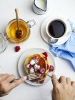 Homem comendo panquecas com framboesas frescas e mel no café da manhã. , vista superior — Fotografia de Stock