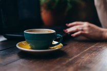 Woman hand next to a cup of coffee — Stock Photo