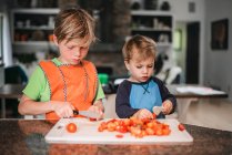 Deux jeunes enfants aident à cuisiner dans la cuisine — Photo de stock