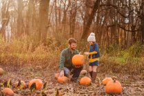 Young girl and father carrying pumpkins in a pumpkin patch — Stock Photo