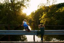 Due giovani ragazzo pesca fuori di un ponte al sole della sera — Foto stock