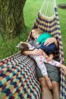 Père jouant avec deux jeunes enfants sur hamac — Photo de stock