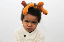 Retrato de um menino puxando rostos engraçados usando chifres de Natal — Fotografia de Stock