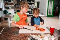 Two young children helping cooking in the kitchen — Stock Photo