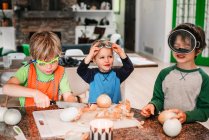 Three young children helping cooking in the kitchen — Stock Photo