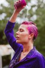 Жінка з рожевим волоссям наливає воду на голову — стокове фото