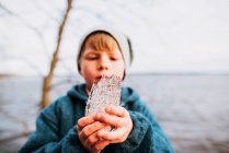 Молодой мальчик держит кусок льда на природе — стоковое фото