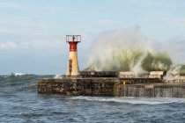 Faro con onda di tempesta di rottura al molo — Foto stock