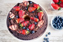 Chocolate cake with fresh strawberries and blueberries on a wooden table — Stock Photo