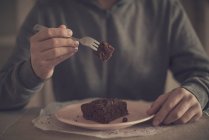 Человек держит кусок шоколадного торта на вилке — стоковое фото