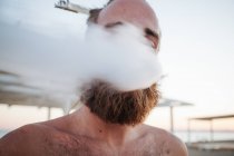 Retrato de un hombre con una pluma en el pelo fumando - foto de stock