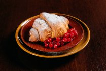 Süßes Croissant mit roten Johannisbeeren, Nahaufnahme — Stockfoto