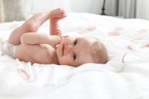 Baby-Mädchen, die auf einem Bett liegend — Stockfoto