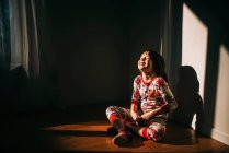 Menina sentada no chão em seu pijama rindo — Fotografia de Stock