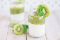 Dos ollas de yogur natural con kiwi y menta fresca - foto de stock