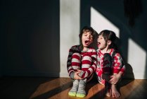 Boy and girl sitting on the floor yawning — Stock Photo