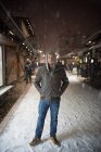 Ritratto di un uomo in piedi in una strada della città sulla neve — Foto stock