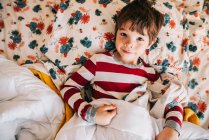 Retrato de cerca del niño sonriente acostado en la cama - foto de stock