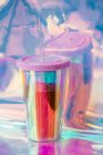 Plastic cup with a drinking straw on silver foil — Stock Photo