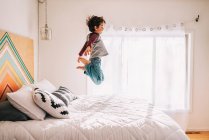 Retrato de niño saltando en una cama - foto de stock