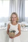Девушка, стоящая у обеденного стола с рождественским подарком — стоковое фото