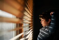 Хлопчик стоїть біля вікна позіхання і розтягування — стокове фото