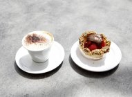 Vista de primer plano de la taza de café y sabroso cupcake con fresa - foto de stock