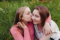 Hija abrazando y besando a su madre - foto de stock