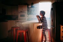 Junge sitzt in Küche und frühstückt im Morgenlicht — Stockfoto