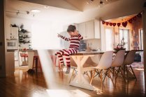Garçon assis sur la table de salle à manger chantant et dansant — Photo de stock