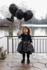 Happy girl holding a bunch of balloons — Stock Photo
