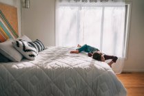 Мальчик катается по кровати дома — стоковое фото
