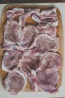 Filetes de cerdo crudos con especias en una tabla de cortar - foto de stock