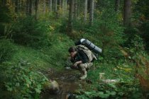 Un homme boit de l'eau d'un ruisseau, Ukraine — Photo de stock