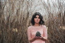 Портрет жінки, що стоїть в лісі, тримає сосновий конус — стокове фото