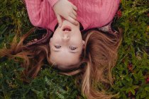 Здивована дівчина лежить на траві з розпростертим волоссям — стокове фото