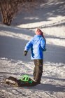 Хлопчик тягне санки на сніг взимку — стокове фото