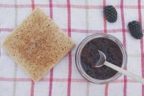 Кусок тоста с горшком ежевичного варенья — стоковое фото