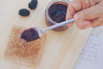 Man putting blackberry jam on toast — Stock Photo