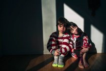 Мальчик и девочка сидят на полу, прислонившись к стене — стоковое фото