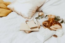 Загорнутий подарунок, блокнот і прикраси на ліжку — стокове фото