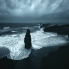 Vista panorámica de las pilas de mar de Reynisdrangur frente a la playa de arena negra, Reynisfjara, Islandia - foto de stock