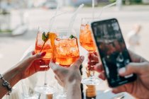 Three women making a celebratory toast with aperol spritz cocktails — Stock Photo