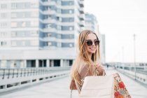 Retrato de una mujer sonriente llevando bolsas de compras - foto de stock