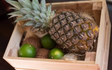Vista da vicino di ananas e lime in una cassa di legno — Foto stock