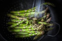 Asparagus in a colander being washed, closeup view — Stock Photo